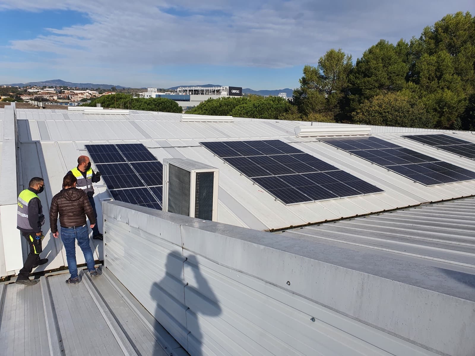 Técnicos inspeccionando una instalación solar sobre el techo de una nave industrial